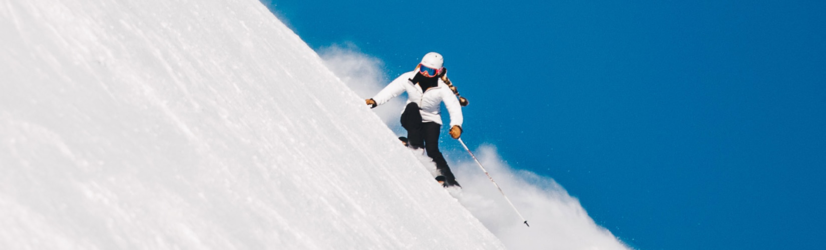 Woman in white jacket skiing; Photo by Nicolai Berntsen on Unsplash